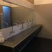 Tardaba mucho en un baño público, fueron a verlo y estaba robando las canillas